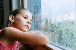 young child looking out rainy window