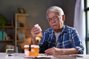 man sitting examining one pill bottle against three others