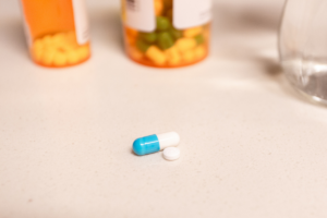 blue and white pills on table next to prescription bottles