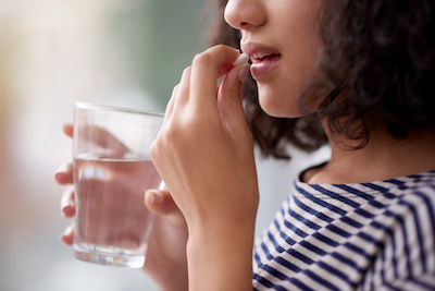 girl taking pill with water