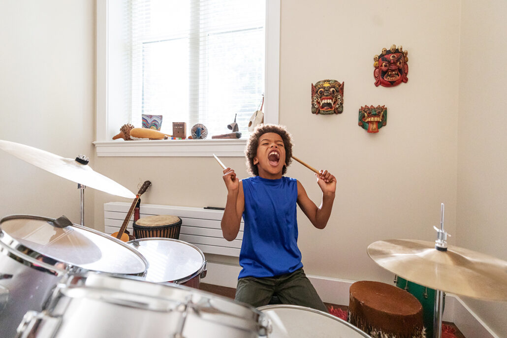 boy in blue shirt drumming with mouth open