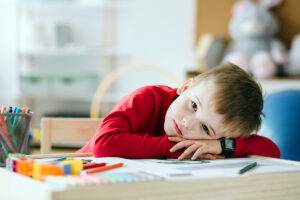 little boy sitting at desk with head resting on hands