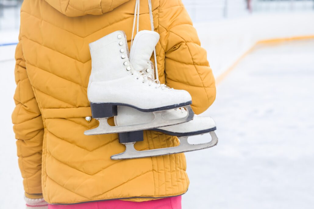 person holding ice skates wearing yellow jacket