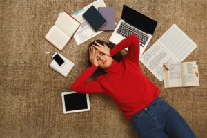 girl lying in middle of books and computer
