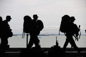 men in military carrying bags