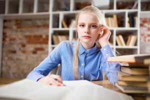 young girl sitting at desk with paper