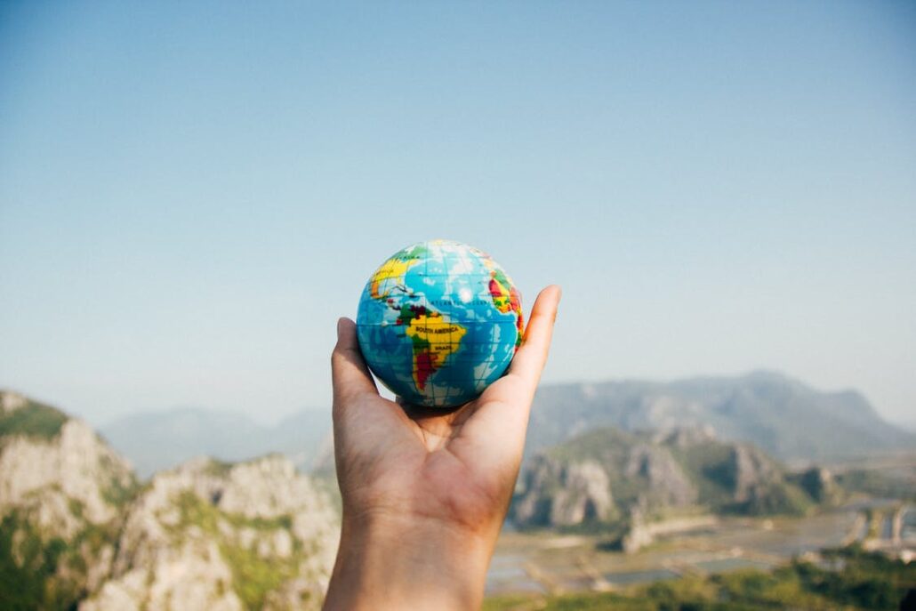 hand holding globe in front of mountain scene