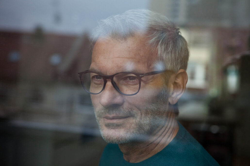 adult man staring out window
