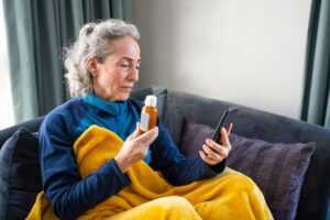 older woman holding meds on phone consult with doc